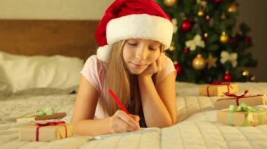 Noel için dekore edilmiş bir iç mekandaki çocuk Noel Baba 'ya bir mektup yazar.