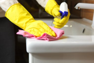 Kadınlar banyodaki lavabo ve musluğu temizler, temizlik ve dezenfeksiyon yapar.