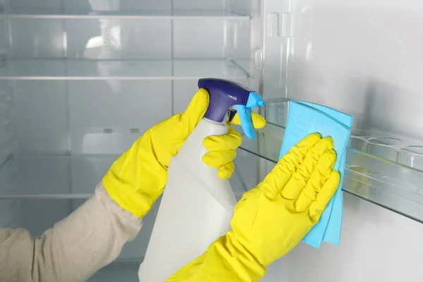 Eine Frau wäscht den Kühlschrank mit Desinfektionsmitteln in Großaufnahme. lizenzfreie Stockfotos