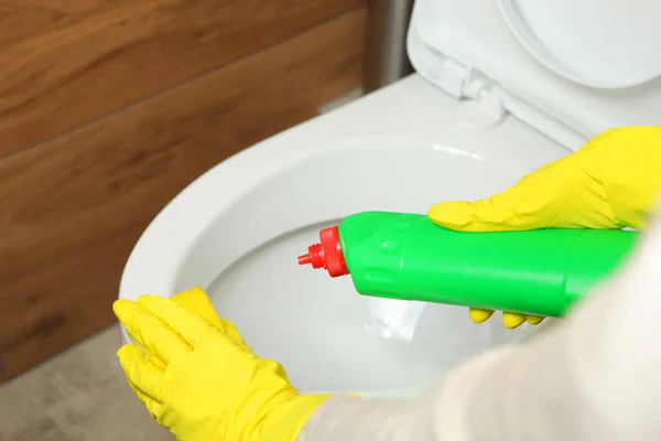 Frau wäscht und desinfiziert Toilettenschüssel mit Waschmittel in Nahaufnahme Stockbild