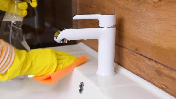 Frau säubert Waschbecken und Wasserhahn im Bad, reinigt und desinfiziert — Stockvideo