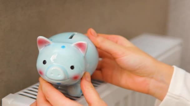 Pig piggy bank on a radiator indoors close-up. Heating concept. — Stockvideo