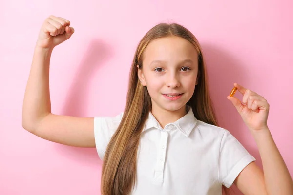 Nastoletnia dziewczyna trzyma w dłoniach kapsułkę omega 3 na kolorowym tle. — Zdjęcie stockowe