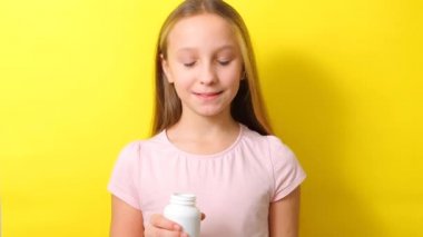 Genç kız, Omega 3 kapsüllerini renkli arka planda yakın plan çekimde kullanıyor.