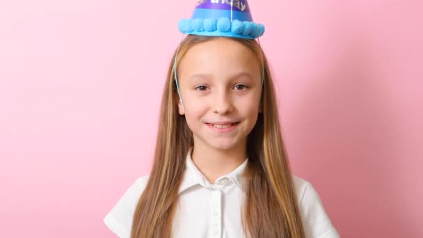 お祝いの帽子をかぶった10代の女の子が曲を吹く。誕生日のコンセプト — ストック動画