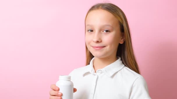 Tonårstjej tar omega 3 kapslar på en färgad bakgrund närbild — Stockvideo