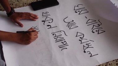 Bangladeşli kız izci takımından bazı kızlar Dhaka tren istasyonunda oturan Covid-19 salgınından korunmak için el yazısıyla pankart hazırlıyorlar..