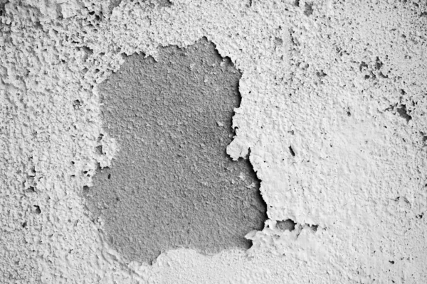 White damp wall showing paint cracking open and breaking or peeling off. The fragile white lining of the walls. Abstract cracked and swollen black-white background. Macro close-up view.