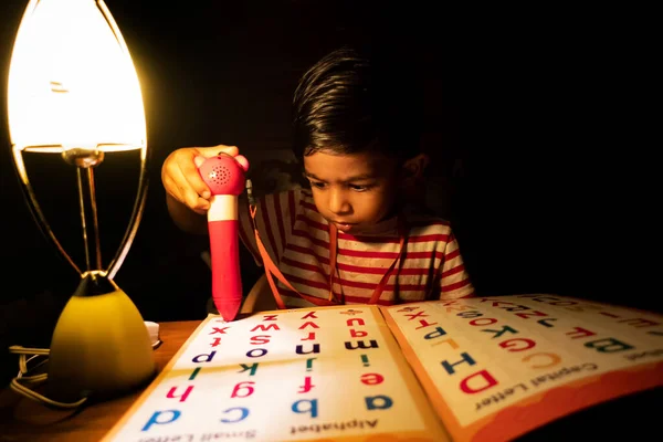 집에서 저녁에 충전기등을 사용하여 알파벳을 배우고 있습니다 불밑에서 공부하는 아시아인 로열티 프리 스톡 이미지