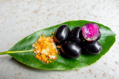 Baharatlı karışık tuz ve yeşil yapraklı siyah Java eriği meyvesi. Olgun sezyum camini meyvesini elle yemenin bir yolu. 4k yakın çekim videosu.