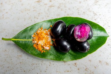 Baharatlı karışık tuz ve yeşil yapraklı siyah Java eriği meyvesi. Olgun sezyum camini meyvesini elle yemenin bir yolu. 4k yakın çekim videosu.