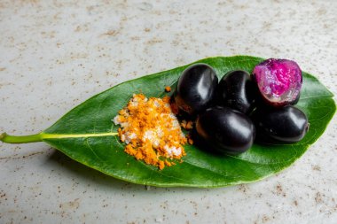 Baharatlı karışık tuz ve yeşil yapraklı siyah Java eriği meyvesi. Olgun sezyum camini meyvesini elle yemenin bir yolu. 4k yakın çekim videosu.