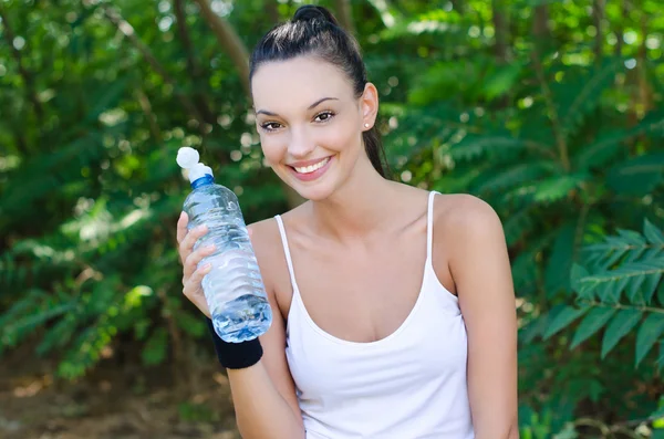 Bella ragazza ridendo tenendo una bottiglia d'acqua all'aperto — Foto Stock