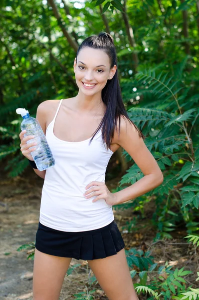 Beautiful girl laughing holding a bottle of water outdoors — Stock Photo, Image