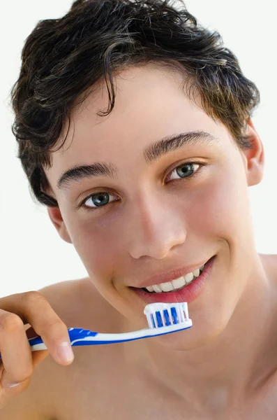 Красивый молодой человек улыбается и держит зубную щетку — стоковое фото