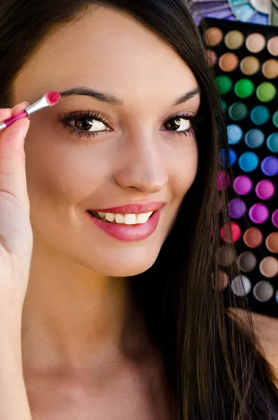 Hermosa chica sonriendo sosteniendo un cepillo de maquillaje — Foto de Stock