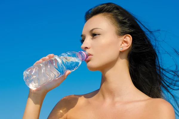 Beautiful brunette girl drinking from a bottle of water — Stock Photo, Image