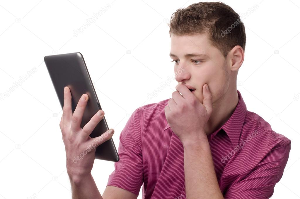 Young man reading a shocking news on the tablet.