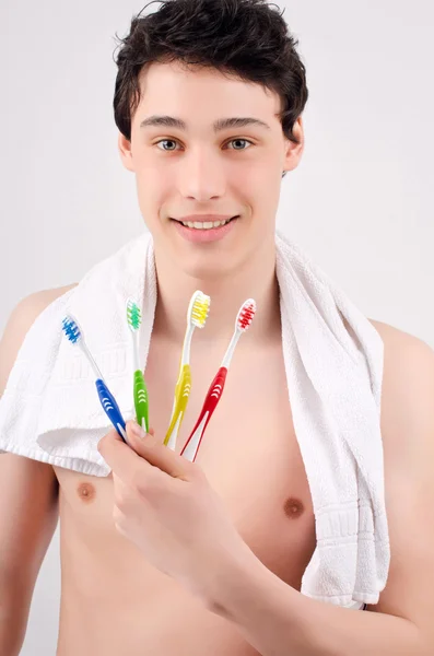 Man met tandenborstels van verschillende kleuren. — Stockfoto