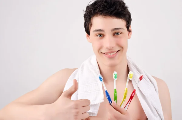 Man holding toothbrushes of various colors. Thumbs up. — Stockfoto