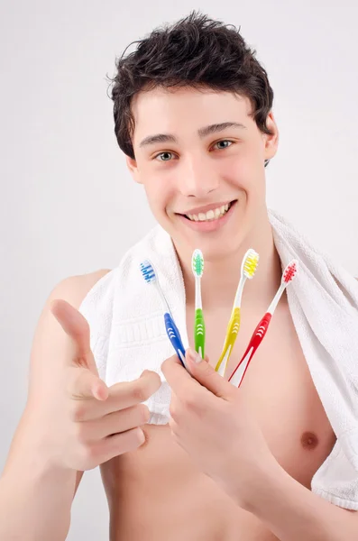 Man met tandenborstels van verschillende kleuren. wijzend op u. — Stockfoto