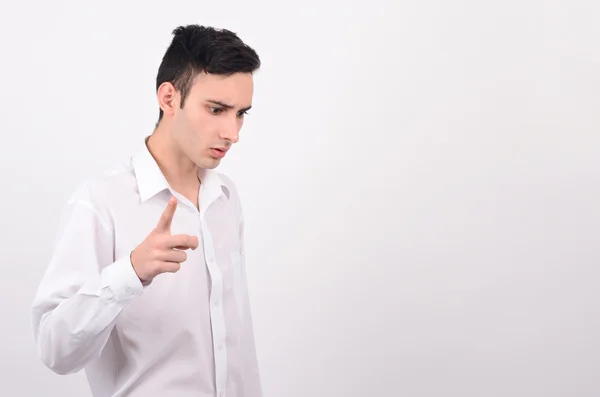 Jonge man in wit overhemd naar beneden te kijken en met de vinger wijzen. — Stockfoto