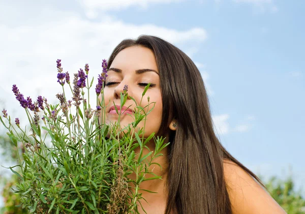 Krásná žena v zahradě voní květiny. — Stock fotografie