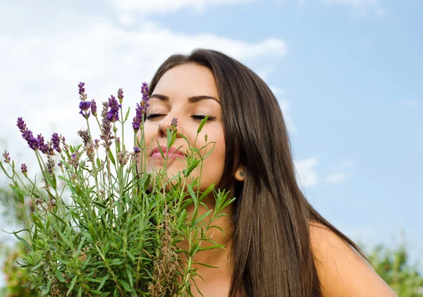 Beautiful woman in the garden smelling flowers. — Stock Photo, Image