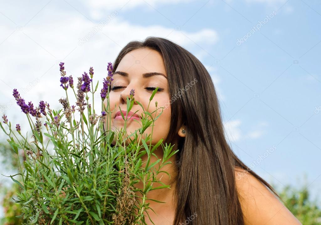 Beautiful woman in the garden smelling flowers.