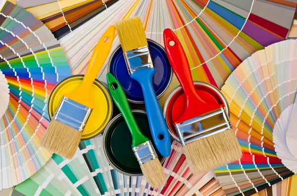 Paint cans and brushes on stripes of color sample. — Stock Photo, Image