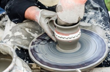 Close-up of hands making pottery from clay on a wheel. clipart