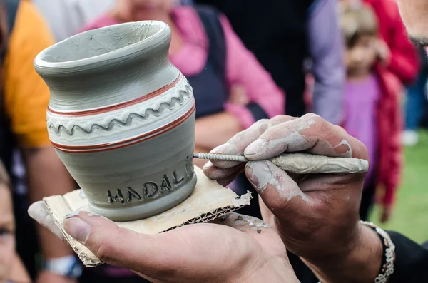 Close-up on artist hands personalizing a clay jug by writing the name of a person. — Stock Photo, Image