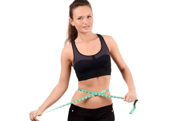 Beautiful fit girl measuring her waist with a green measuring tape in inch. — Stock Photo, Image