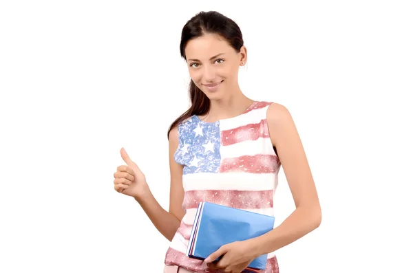 Estudante americana bonita com bandeira dos EUA em sua blusa segurando livros e assinando polegares para cima . — Fotografia de Stock