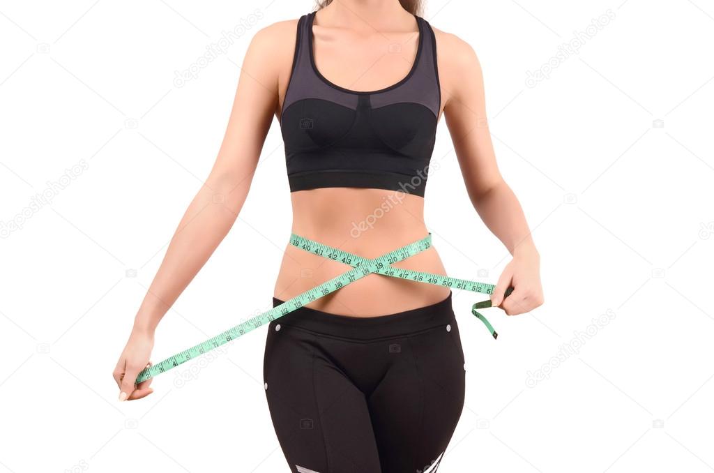 Close up on fit girl abdomen with green measuring tape around the waist.