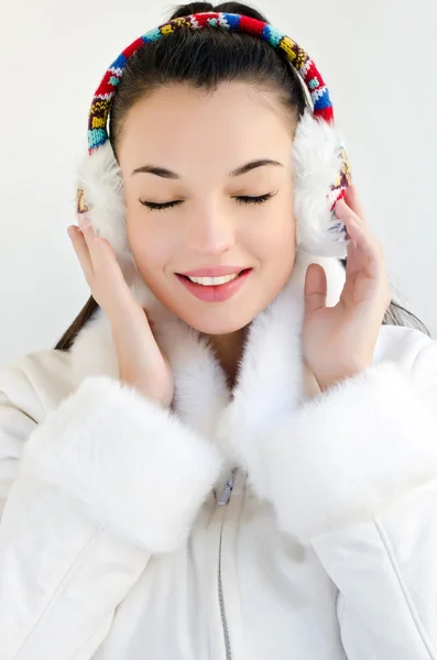 Atrakcyjna dziewczyna nosi biały płaszcz i nauszniki, oczy zamknięte. — Zdjęcie stockowe