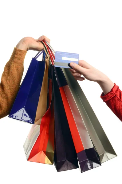 Main d'homme tenant de nombreux sacs à provisions, main de femme tenant une carte de crédit . — Photo