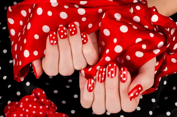 Close up on beautiful female hands with cute red manicure with white dots. — Stock Photo, Image