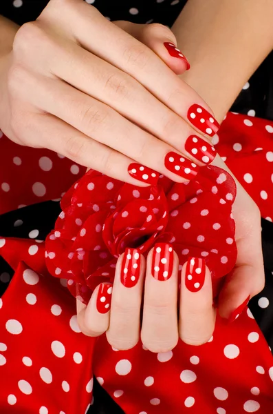 Close-up op mooie vrouwelijke handen met schattige rode manicure met witte stippen. — Stockfoto