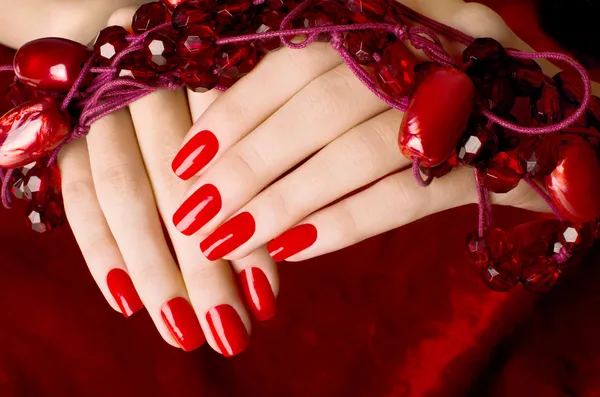 Close-up em belas mãos femininas com manicure vermelho sexy . Imagens Royalty-Free