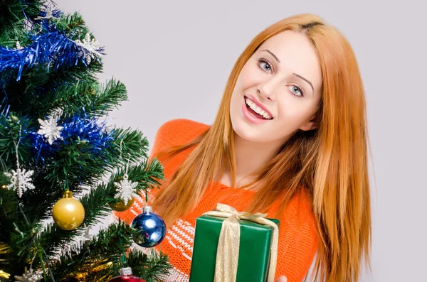 Mooie jonge vrouw die lacht biedt u een kerstcadeau. — Stockfoto