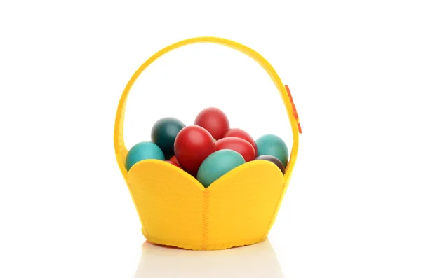 Colorful hand dyed easter eggs in a yellow basket. — Stock Photo, Image