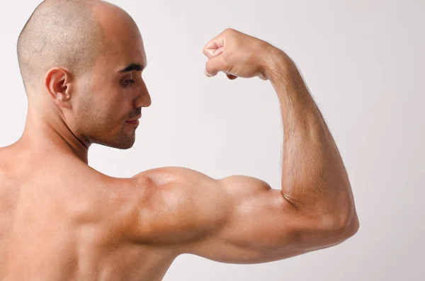 Hombre en forma en topless posando con el brazo hacia arriba mostrando sus bíceps . —  Fotos de Stock