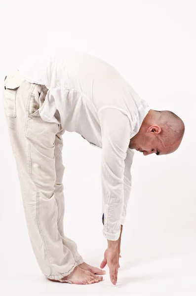 Man doing yoga leaning in front to the ground touching the feet with the arms. — Stock Photo, Image