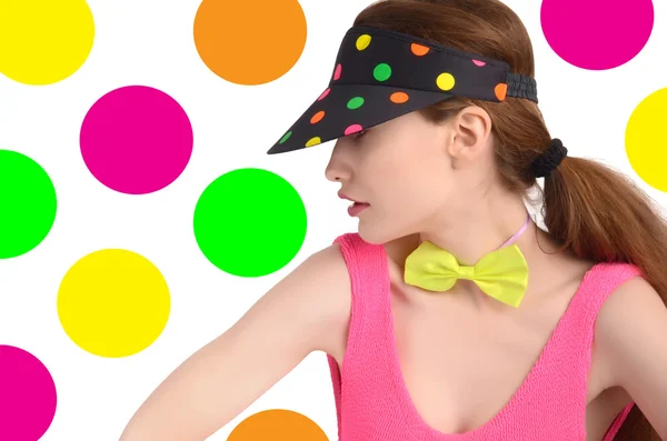 Girl wearing a colorful polka dotted visor and a neon green bowtie. — Stock Photo, Image