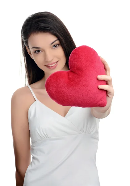 Beautiful brunette girl holding in front a red heart. Happy woman, Valentine day. Focus on the heart, blur on the model. — Stock Photo, Image