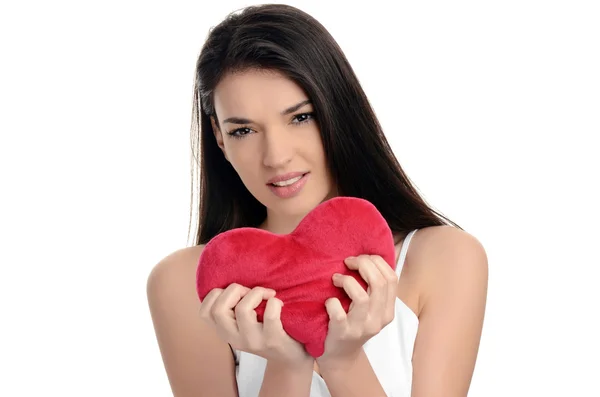 Beautiful brunette girl holding a red heart. Heart broken, loveless, angry on love. Woman tearing up a heart. Valentine day. — Stock Photo, Image