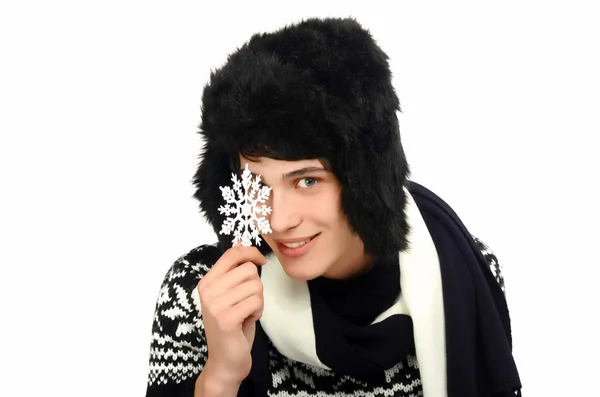 Portrait of a handsome man dressed for a cold winter holding up a big snowflake. — Stock Photo, Image