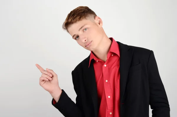 Retrato de um jovem homem de negócios usando um terno e uma camisa vermelha apontando para o lado . — Fotografia de Stock