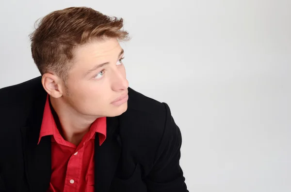 Retrato de um jovem homem de negócios vestindo um terno preto e uma camisa vermelha olhando para o lado. Homem olhando para cima a partir do perfil . — Fotografia de Stock